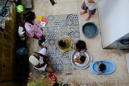 Isis Abena, de 35 anos, e sua filha Ainá, de 2, no pátio com seus vizinhos em Salvador.