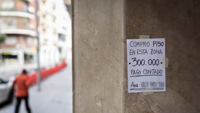 Un cartel colgado en un portal anuncia la compra de un piso con pago al contado en Barcelona.
