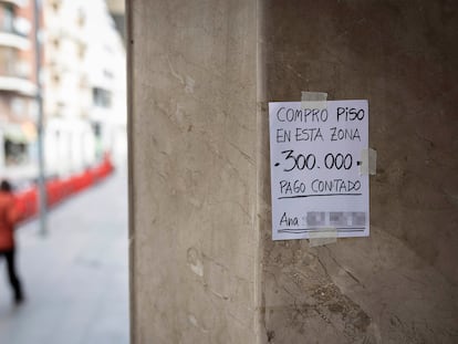 Un cartel colgado en un portal anuncia la compra de un piso con pago al contado en Barcelona.