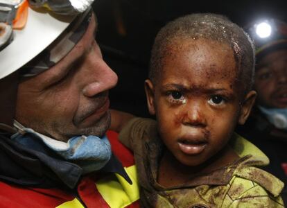 Bomberos, policías y personal de rescate españoles participaron activamente en las labores de salvamento. En la foto, el bombero español del Grupo de Rescate de la Junta de Castilla y León, Óscar Vega Carrera , con el niño Redjeson Hausteen Claude en brazos, tras rescatarlo de entre los escombros de su casa en Puerto Príncipe.