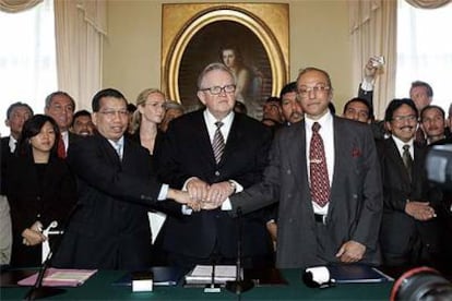 El negociador indonesio, Hamid Awaluddin (izquierda), estrecha la mano del líder rebelde Malik Mahmud, en presencia del mediador finlandés, Martti Ahtisaari, tras la firma del acuerdo de paz en Helsinki.