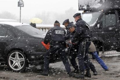 Unos policías empujan un coche en medio de la tormenta de nieve que ayer cayó sobre París.