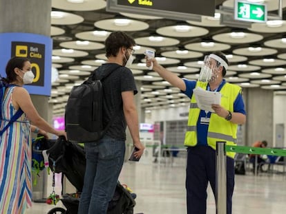 Un operario del aeropuerto de Madrid-Barajas controla la temperatura a unos viajeros el pasado lunes.