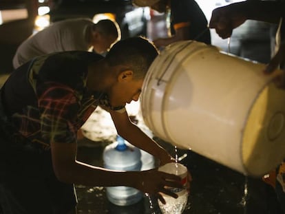 Un grupo de personas recoge agua durante el apagón en Caracas. 