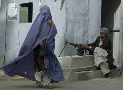 Una afgana con <i>burka</i> pasa ante un miliciano antitalibán cerca del consulado iraní en Herat.