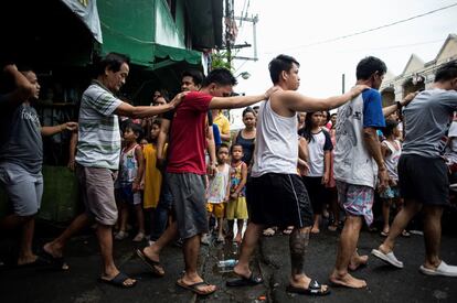 Un grupo de hombres es detenido para la identificación después de que los agentes de policía llevasen a cabo una incursión antidrogas a gran escala en una comunidad de barrios marginales en Manila. Según la policía, un residente fue asesiando durante la redada.