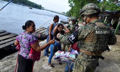 Un miembro de la Marina revisa la identificación de una mujer guatemalteca que cruzó el río Suchiate.