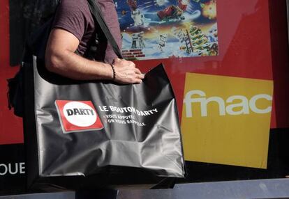 Un hombre pasa con una bolsa de Darty frente a una tienda de Fnac en Niza
