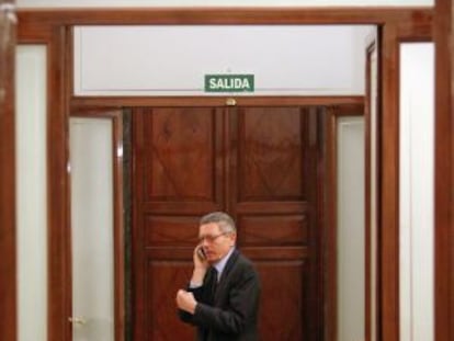 El ministro de Justicia, Alberto Ruiz-Gallardón, habla por el teléfono móvil en un pasillo del Congreso.