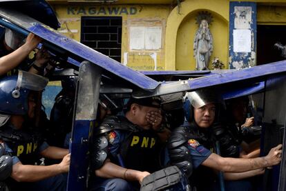 Policías se protegen durante la demolición de unas viviendas en un barrio chabolista en Ciudad Quezón en Manila. El Gobierno filipino ha decretado el desahucio de 500 familias afincadas en este barrio de chabolas para dar paso a la construcción de un nuevo distrito financiero en la ciudad.