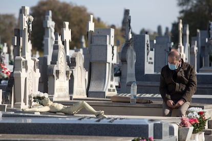 Un hombre visita la tumba de sus familiares en el cementerio de la Almudena de Madrid, este domingo. Trescientos agentes de la Policía Municipal de Madrid, apoyados por tres drones con cámara y altavoces, vigilarán que durante el puente de Todos los Santos no haya aglomeraciones en los cementerios.