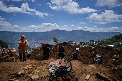 Varios hombres trabajan en la limpieza y el rescate tras el deslizamiento de tierra.