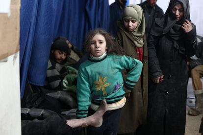 Una niña siria espera junto a su padre herido en una clínica en la zona controlada por los rebeldes de Douma, al este de Damasco, tras los ataques aéreos reportados por las fuerzas del régimen.