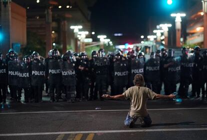Un manifestante se arrodilla frente a miembros de la policía durante unas protestas tras un mítin del presidente estadounidense Donal Trump, en Phoenix (EE UU).