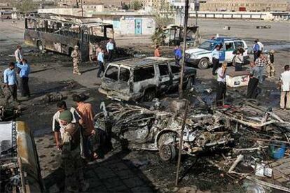 Policías y soldados iraquíes observan los restos de uno de los coches bomba que explotaron en Bagdad.