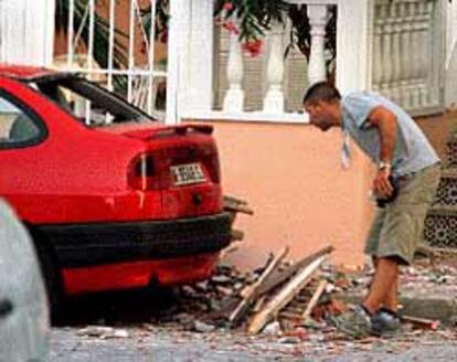 Un agente observa los daños causados por la explosión en un vehículo junto al bloque de apartamentos.