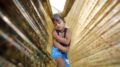 Un niño duerme en una hamaca de tela en una carretera de Nueva Delhi (India).