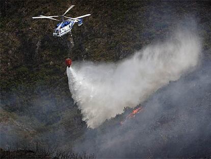Un helicóptero descarga agua sobre el incendio de la Serra de l'Almirant.