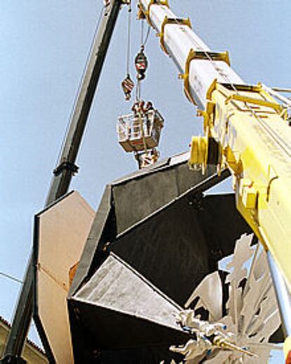 Dos operarios afianzan el monumento para evitar su derrumbamiento.