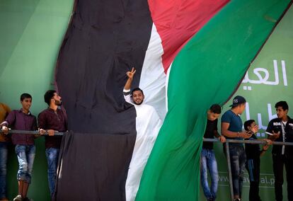 Un hombre despliega una gran bandera palestina durante una reunión en el norte de la Franja de Gaza para la llegada del primer ministro palestino, Rami Hamdallah.