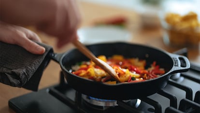 Una sartén llena de verduras mientras alguien cocina.