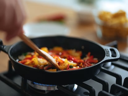 Una sartén llena de verduras mientras alguien cocina.