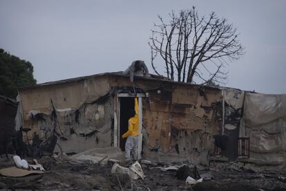 El cartón, el plástico o la madera con los que se levantan las casas del asentamiento son materiales muy precarios, que arden con facilidad. En la imagen, dos habitantes trabajan en arreglar una chabola afectada por el fuego.