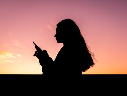 Una adolescente consulta su teléfono móvil.