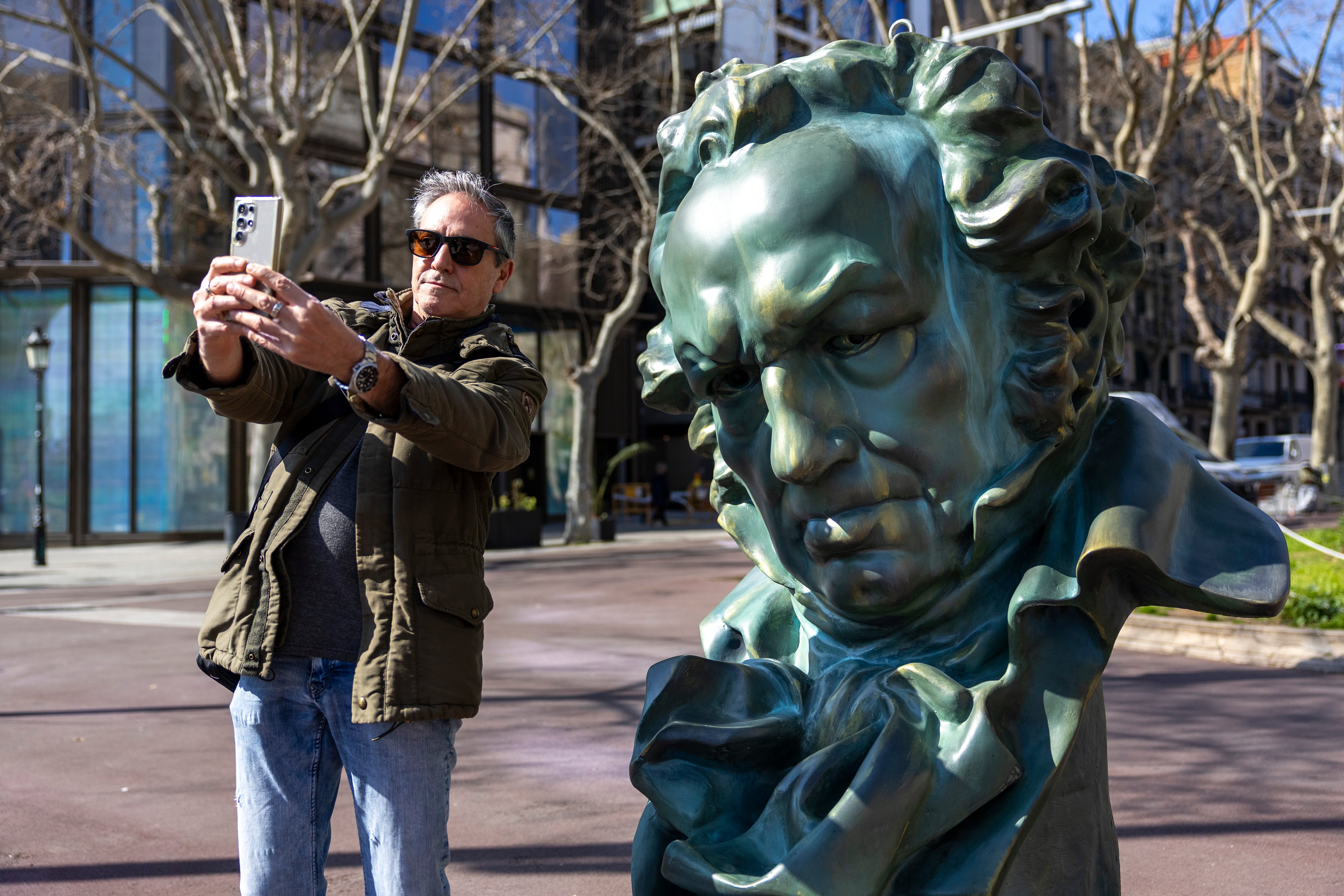 Un hombre se hace un selfi, el jueves, con uno de los cabezones de los Goya repartidos por Barcelona. 
