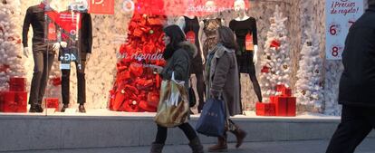 Dos mujeres pasan delante de un escaparate con motivos navideños.