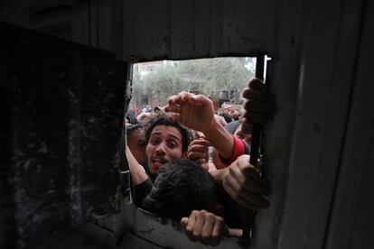 Palestinos desplazados se asoman a la ventana de una panadería para intentar conseguir pan en el campo de refugiados de Nuseirat, este jueves en la Franja.