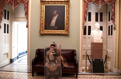 Un partidario del presidente Donald Trump toma asiento lejos de la acción en el segundo piso del Capitolio de EE. UU.