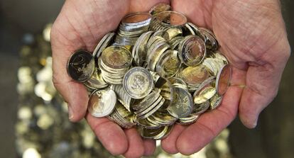 Un hombre sostiene varias monedas de euro.