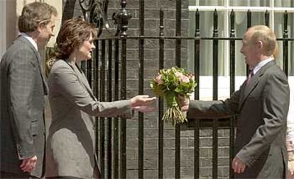 Vladímir Putin ofrece un ramo de flores a Cherie Blair en presencia del primer ministro británico.