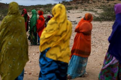 Unas mujeres observan cómo los trabajadores humanitarios que han llegado a la zona comprueban el estado de los cadáveres de los animales diseminados por el terreno en la ciudad de Borama.