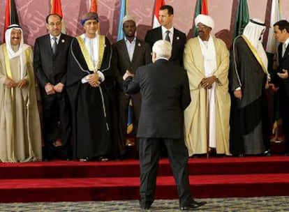 El presidente palestino, Mahmud Abbas, de espaldas, saluda a los dirigentes árabes, entre ellos Al Bashir (tercero por la derecha), en Doha.