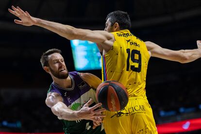 El escolta del Unicaja Tyler Kalinoski da una asistencia ante el pívot del Lenovo Tenerife Gio Shermadini.