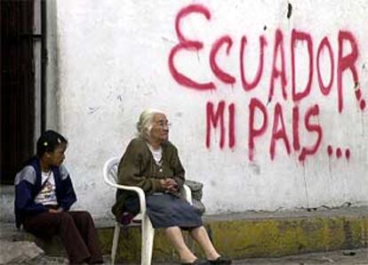 Una anciana y una niña, delante de una pintada en una calle de Quito en el día de las elecciones.
