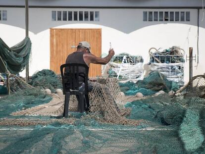 Un pescador repara les xarxes de pesca al port de Barcelona.
