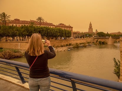 Una mujer hace una fotografía con su móvil del aspecto que presentaba la ciudad de Murcia, el lunes.