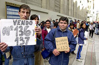 Dos desempleados venden su puesto en una de las filas en Buenos Aires para comprar dólares.
