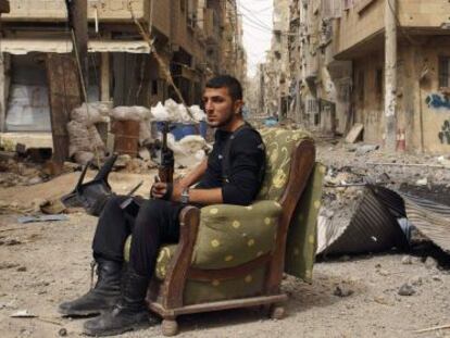 Un miembro del Ej&eacute;rcito Libre Sirio sujeta un arma, sentado en medio de una calle de Deir el Zor, el jueves.