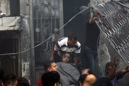 Varios hombres palestinos evacúan del interior de una casa destruida a una mujer herida, tras un ataque Israelí en la ciudad de Gaza.  