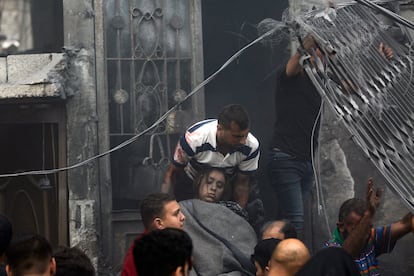 Varios hombres palestinos evacúan del interior de una casa destruida a una mujer herida, tras un ataque Israelí en la ciudad de Gaza.