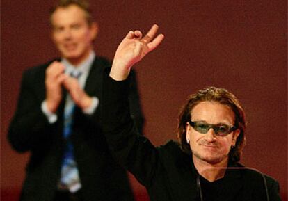 Bono hace la señal de la victoria mientras recibe un calusoro aplauso de Blair al término de su discurso.