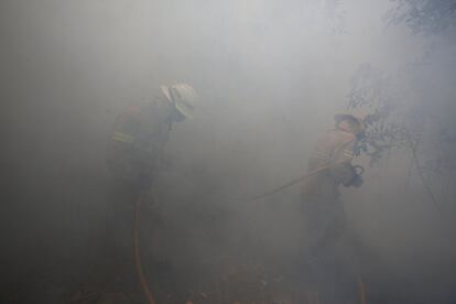 Bomberos trabajan en medio del humo para apagar un incendio forestal cerca de Castanheira de Pera, Portugal.