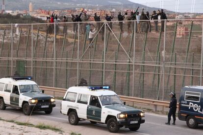 Guardia civiles vigilan que los inmigrantes que han logrado subir a la valla fronteriza no salten a Melilla.