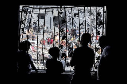 Varias personas miran desde una ventana los trabajos de búsqueda de supervivientes, este martes en Rafah.