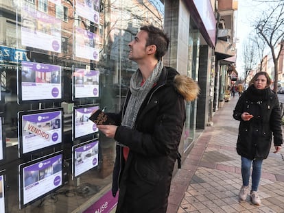 Un joven, tomando nota de pisos en venta en una inmobiliaria, en una imagen de archivo.