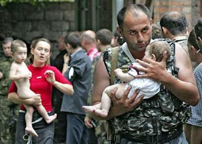 Un soldado traslada en brazos a un bebé hacia el exterior del colegio asaltado, seguido por una mujer con un niño también liberados.